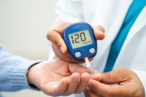 Patient checking blood sugar levels with glucose meter during diabetes doctor visit