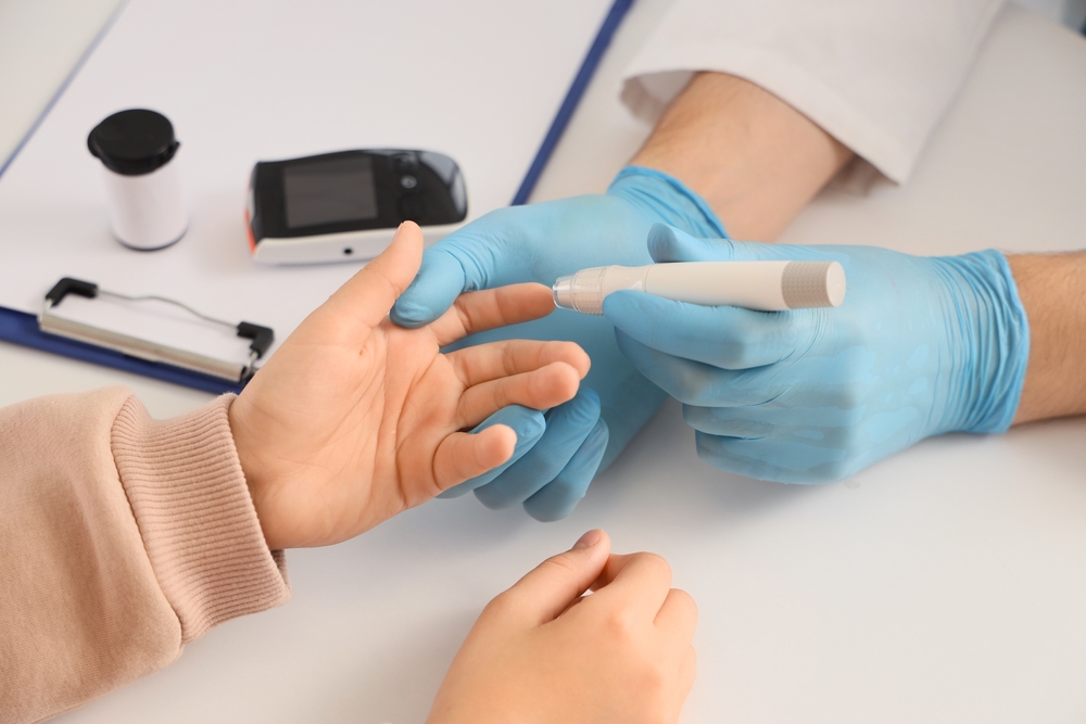 Diabetes doctor performing blood glucose test with glucose meter during patient consultation