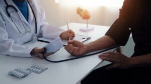 Doctor using stethoscope and blood pressure monitor during high blood pressure evaluation