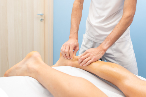 Physical therapist massaging patient's ankle during tendinitis of the ankle treatment session