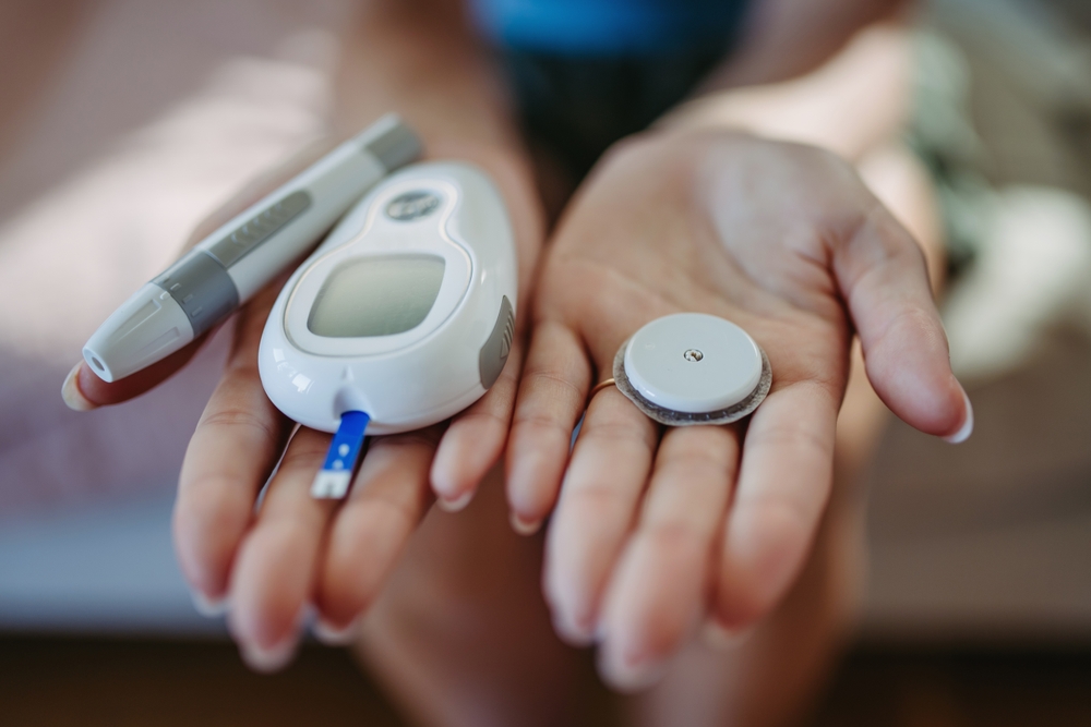 Patient holding glucose meter and continuous glucose monitoring sensor for type 2 diabetes treatment