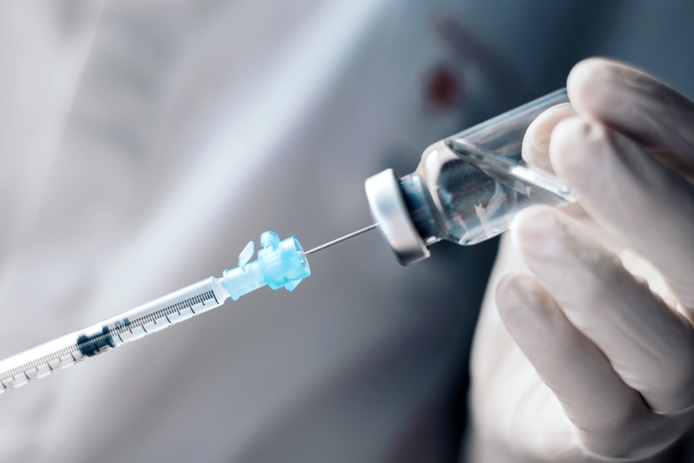 Healthcare provider drawing biotin solution into syringe from vial for patient injection