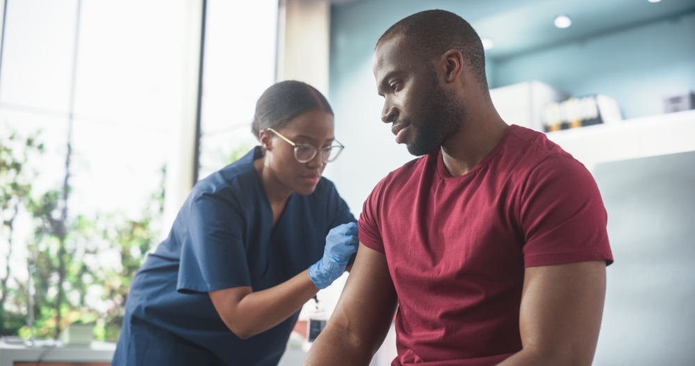Nurse giving BPC 157 peptide injection to male patient's arm in medical office