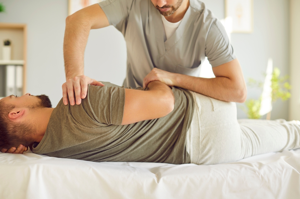 Chiropractic specialist performing hip and lower back adjustment on male patient
