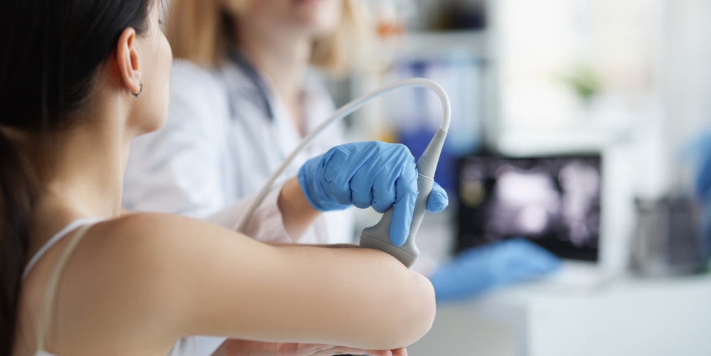Medical professional conducting diagnostic ultrasound with patient and imaging monitor visible