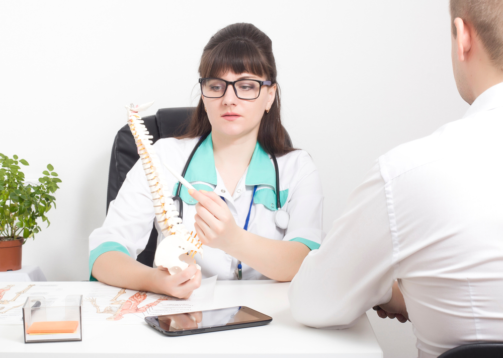 Patient receiving physical therapy for disc bulge treatment with spine model