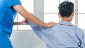 Physical therapist providing frozen shoulder treatment stretching therapy to patient