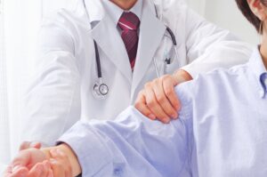 Doctor examining patient's arm mobility during frozen shoulder treatments consultation