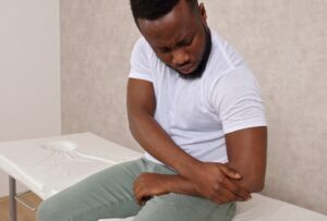 Man experiencing inner elbow pain requiring golf elbow treatment evaluation