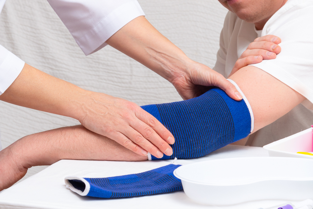 Healthcare provider applying therapeutic elbow brace during golfers elbow treatment session