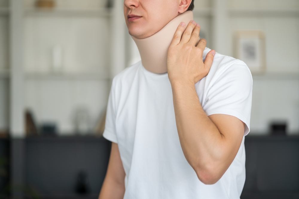 Man wearing cervical collar holding neck during herniated disc treatment neck recovery