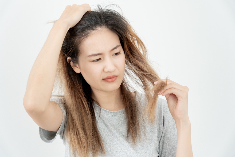 Young woman checking hair quality showing concern about hormonal imbalance symptoms