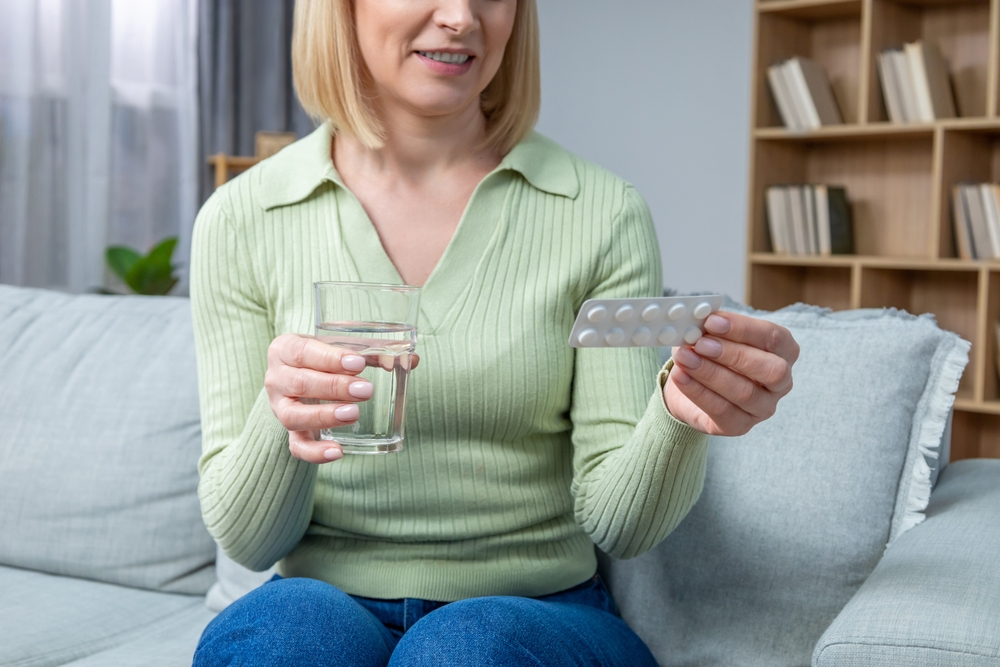 Woman holding glass of water demonstrating daily hormone therapy routine