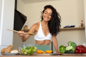 Fit woman preparing healthy metabolism-boosting foods in kitchen for how to metabolize faster