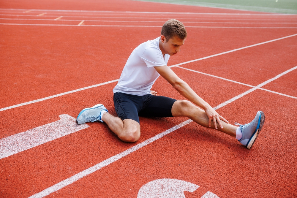 Runner performing stretching exercises demonstrating sports injury prevention