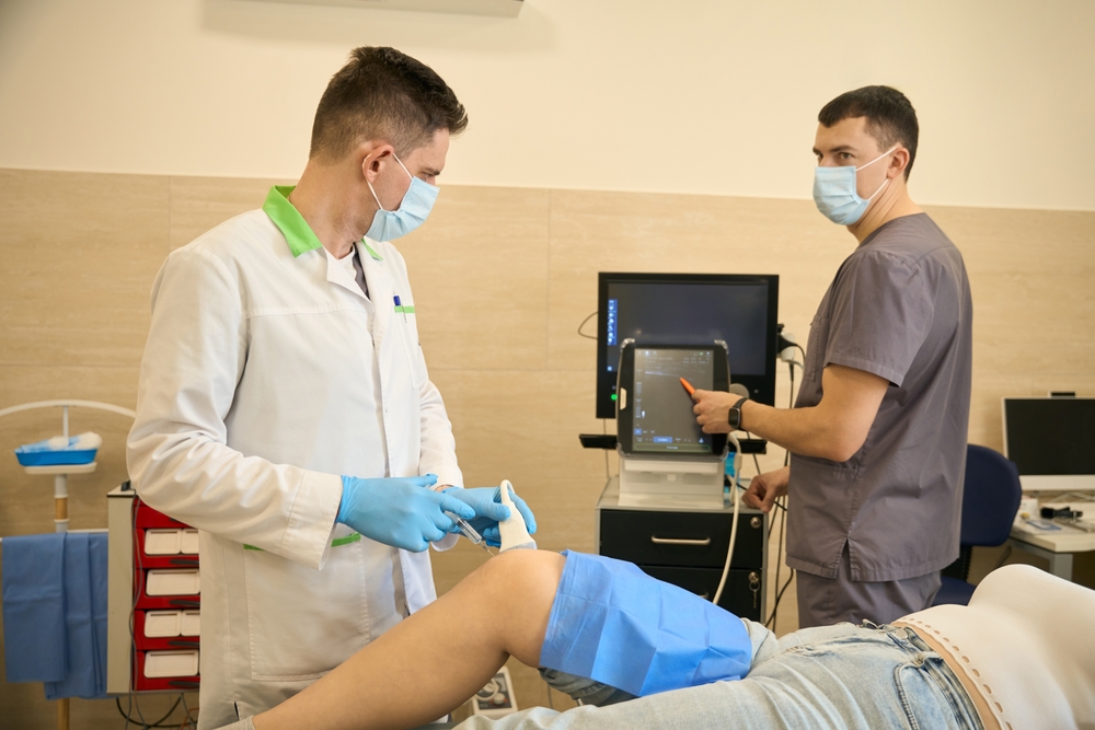 Healthcare providers administering joint injection with ultrasound guidance