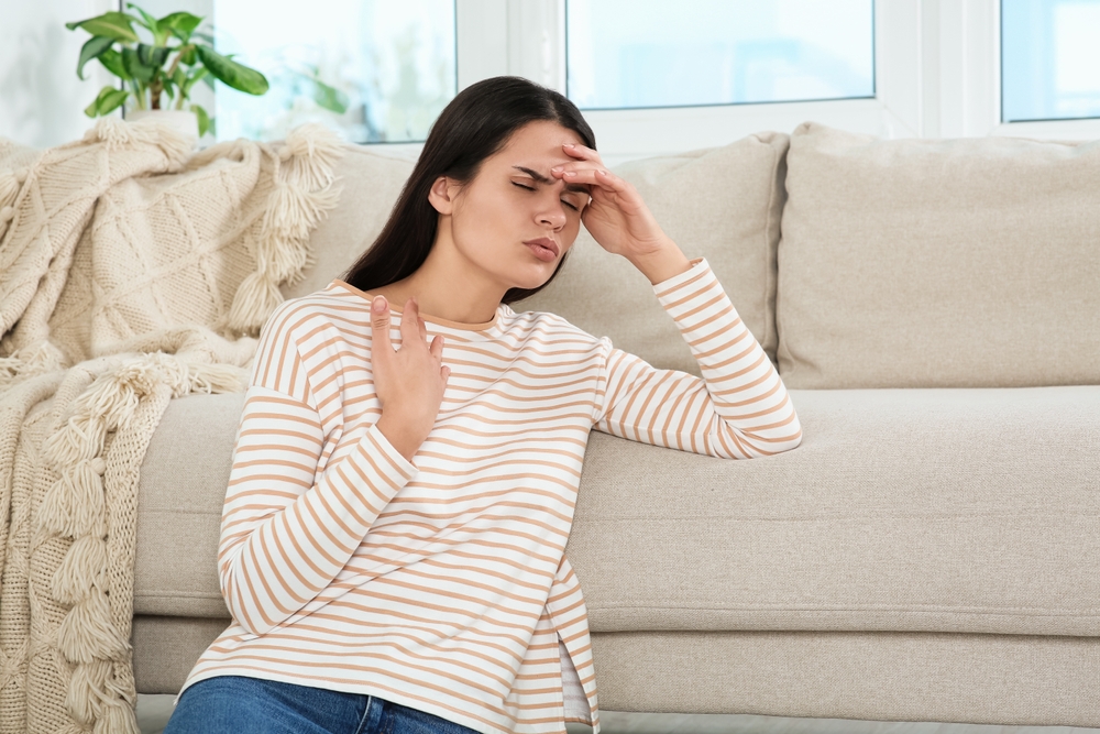 Woman showing signs of hormonal imbalance including fatigue sitting on couch