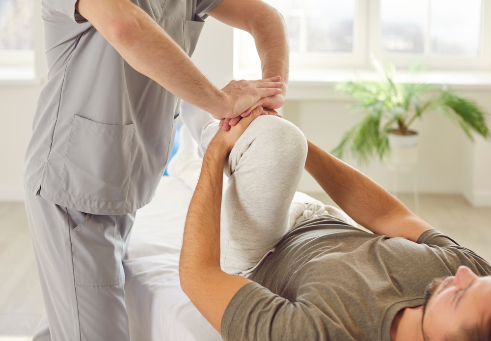 Therapist assisting patient with knee and leg physical therapy