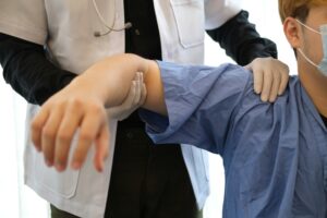Healthcare provider performing shoulder manipulation therapy during bursitis treatment shoulder session