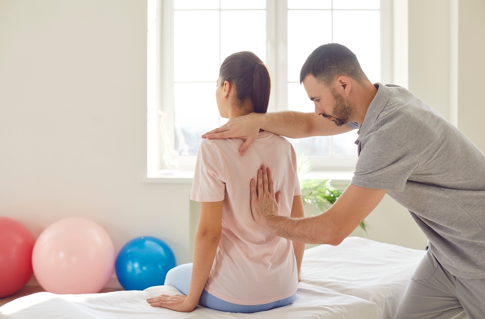 Chiropractor performing spinal adjustment on athletic patient