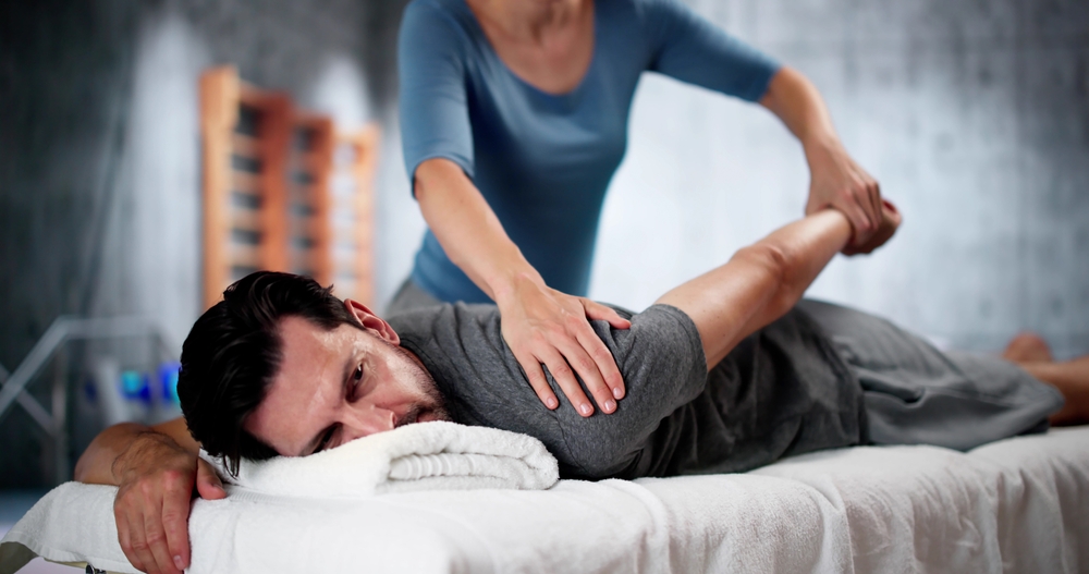 Sports massage therapist working on athlete's shoulder muscles