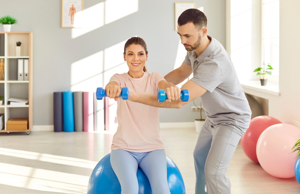 Sports PT guiding athlete through shoulder rehabilitation exercises