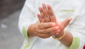 Person holding inflamed hand showing symptoms requiring tendonitis in hand treatment