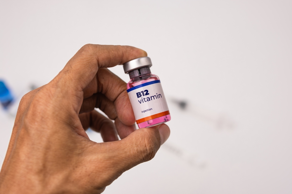 Hand holding vitamin B12 injection vial ready for administration to patient