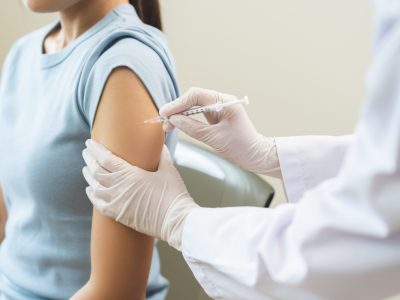 Medical professional preparing biotin injection with syringe and medication vial