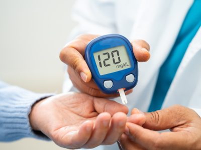 Patient checking blood sugar levels with glucose meter during diabetes doctor visit