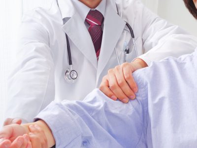 Doctor examining patient's arm mobility during frozen shoulder treatments consultation