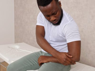 Man experiencing inner elbow pain requiring golf elbow treatment evaluation
