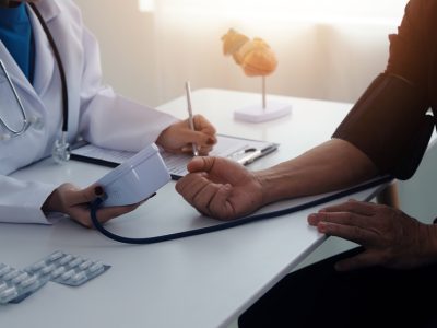 Doctor using stethoscope and blood pressure monitor during high blood pressure evaluation