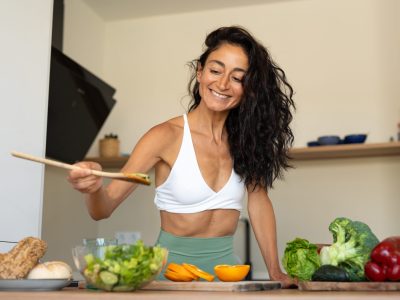 Fit woman preparing healthy metabolism-boosting foods in kitchen for how to metabolize faster