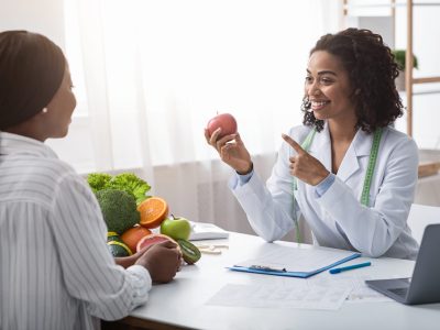 Nutritionist holding fresh vegetables while counseling patient
