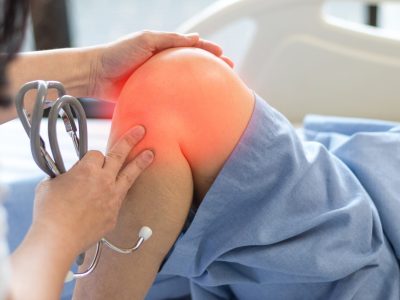Doctor examining adolescent athlete's knee during sports medicine consultation
