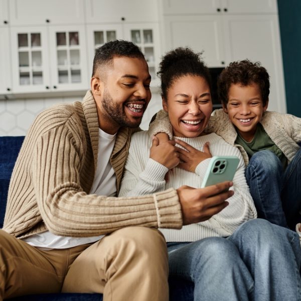 An,African,American,Family,Engrossed,In,A,Smartphone,On,A